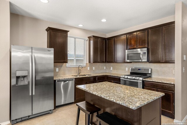 1617 Desert Candle, San Antonio, TX 78245 - kitchen with appliances with stainless steel finishes, a sink, dark brown cabinetry, light stone countertops, and backsplash