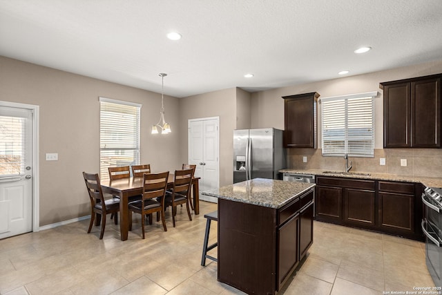 1617 Desert Candle, San Antonio, TX 78245 - kitchen with a sink, stainless steel appliances, tasteful backsplash, dark brown cabinets, and a kitchen island