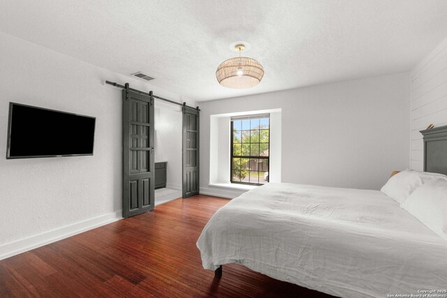 306 Chaparral Crk, Boerne, TX 78006 - bedroom featuring a barn door, wood finished floors, and baseboards