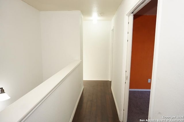 corridor with dark wood finished floors and baseboards