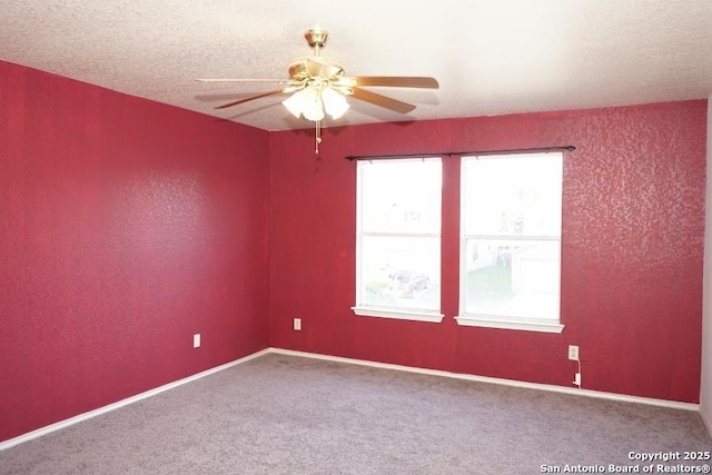 carpeted spare room featuring ceiling fan and baseboards