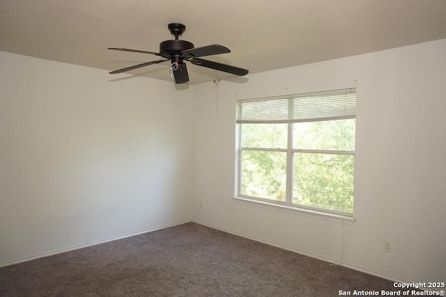 carpeted spare room with a ceiling fan and baseboards