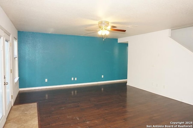 unfurnished room with hardwood / wood-style flooring, a ceiling fan, baseboards, and a textured ceiling