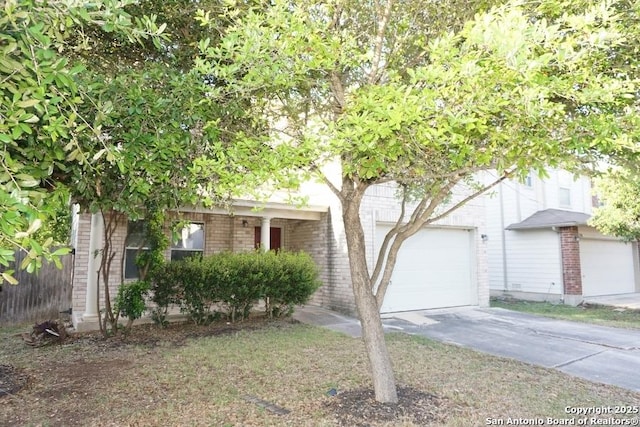 view of property hidden behind natural elements with brick siding, driveway, and fence