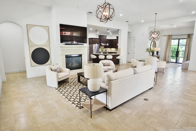 living area featuring recessed lighting, a chandelier, and a glass covered fireplace
