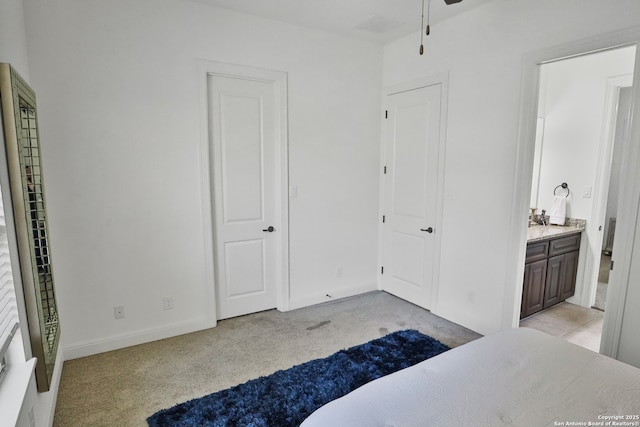 bedroom with light colored carpet, ensuite bath, and baseboards