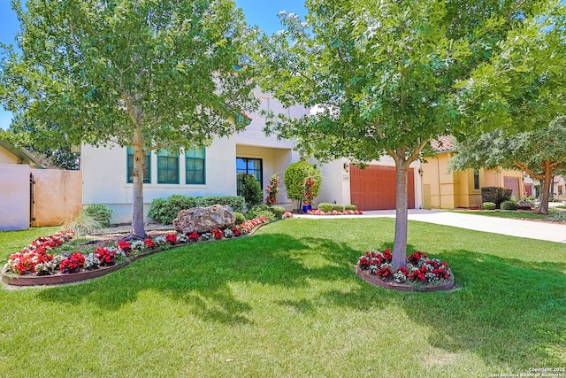 obstructed view of property featuring concrete driveway, an attached garage, a front yard, and stucco siding