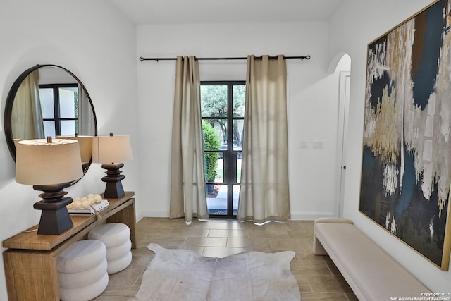 foyer with arched walkways and baseboards