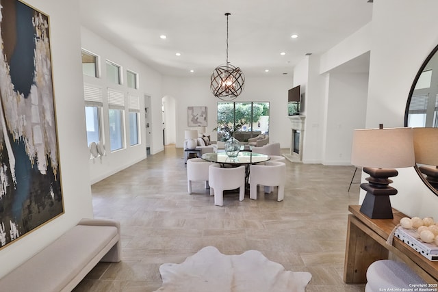 dining room with recessed lighting, arched walkways, a glass covered fireplace, baseboards, and a chandelier