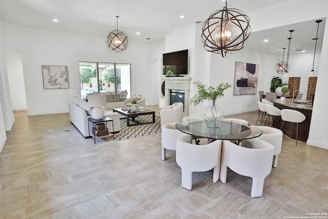 dining room with a chandelier, recessed lighting, a glass covered fireplace, arched walkways, and baseboards
