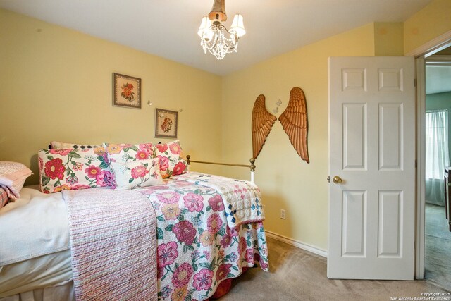 carpeted bedroom with a chandelier and baseboards