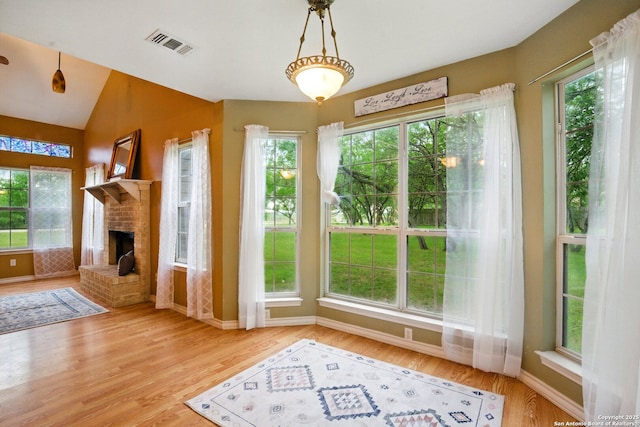 unfurnished living room with healthy amount of natural light, wood finished floors, and vaulted ceiling
