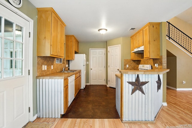 kitchen featuring under cabinet range hood, white appliances, a sink, tasteful backsplash, and tile counters