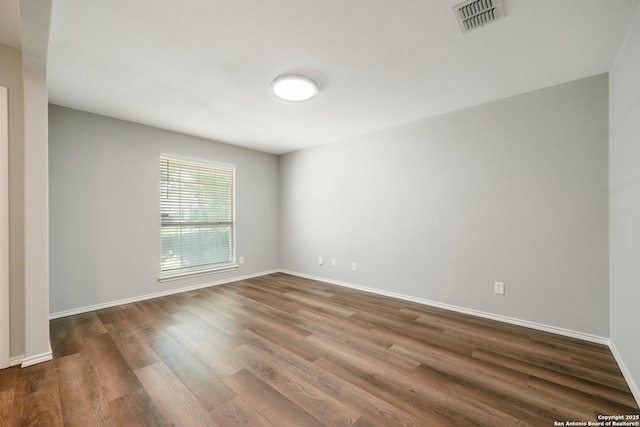 empty room with dark wood-style flooring and baseboards