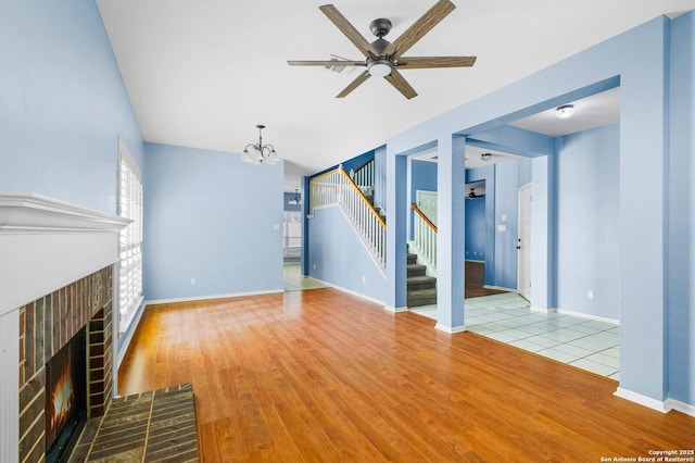 8818 Sarasota Woods, San Antonio, TX 78250 - unfurnished living room with stairs, a fireplace, a chandelier, a ceiling fan, and wood finished floors