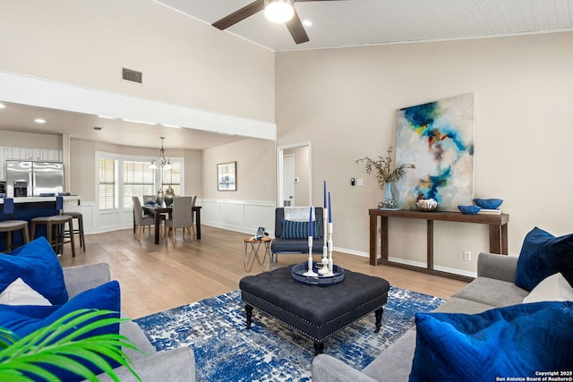 3010 Skyline, Canyon Lake, TX 78133 - living room with light wood-style floors, a ceiling fan, a chandelier, high vaulted ceiling, and wainscoting
