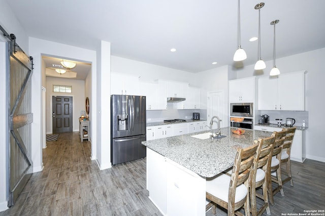 1710 Briar Spg, San Antonio, TX 78245 - kitchen with appliances with stainless steel finishes, a sink, a barn door, under cabinet range hood, and wood finished floors