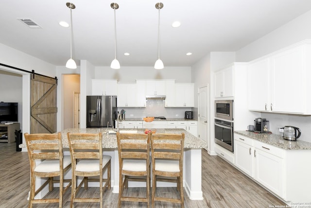 1710 Briar Spg, San Antonio, TX 78245 - kitchen featuring stainless steel appliances, a barn door, a kitchen bar, backsplash, and hanging light fixtures