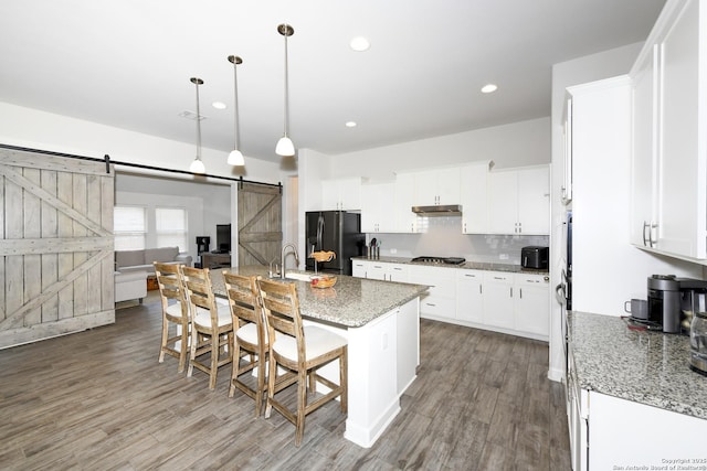 1710 Briar Spg, San Antonio, TX 78245 - kitchen with a barn door, black refrigerator with ice dispenser, stainless steel gas stovetop, wood finished floors, and recessed lighting