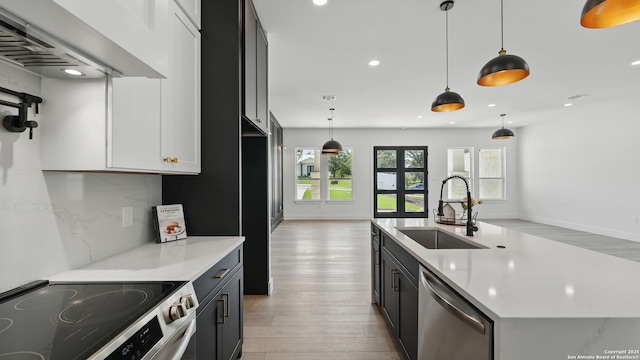 kitchen with appliances with stainless steel finishes, a sink, wall chimney exhaust hood, light wood-style floors, and recessed lighting