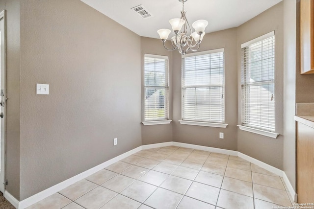 unfurnished dining area with a chandelier, plenty of natural light, light tile patterned floors, and baseboards