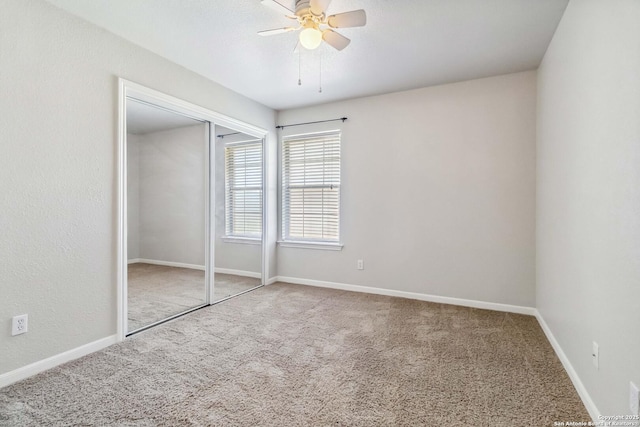 unfurnished bedroom featuring carpet flooring, a closet, baseboards, and ceiling fan