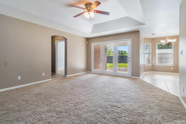 spare room featuring a tray ceiling, arched walkways, a chandelier, light colored carpet, and baseboards