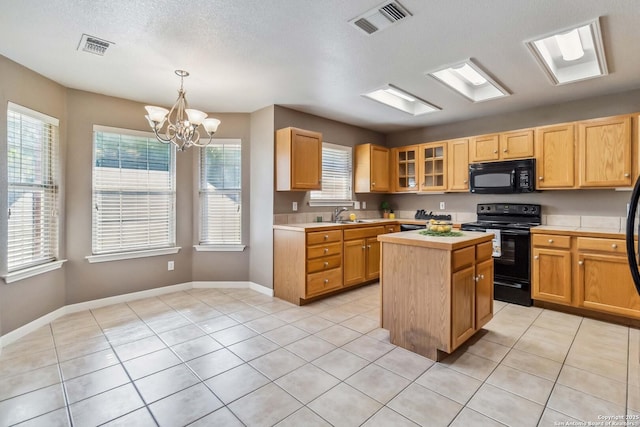 kitchen featuring black appliances, light countertops, a center island, a sink, and a chandelier