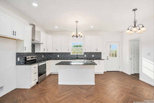 1615 N Guadalupe, Seguin, TX 78155 - kitchen with stainless steel range with electric cooktop, a chandelier, wall chimney exhaust hood, dark countertops, and white cabinets
