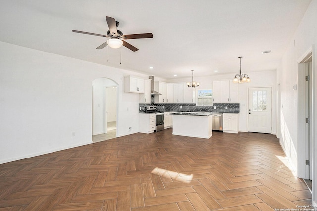 1615 N Guadalupe, Seguin, TX 78155 - kitchen featuring appliances with stainless steel finishes, wall chimney exhaust hood, a chandelier, decorative backsplash, and arched walkways