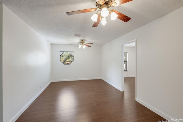empty room with a textured ceiling, a ceiling fan, dark wood-style flooring, and baseboards