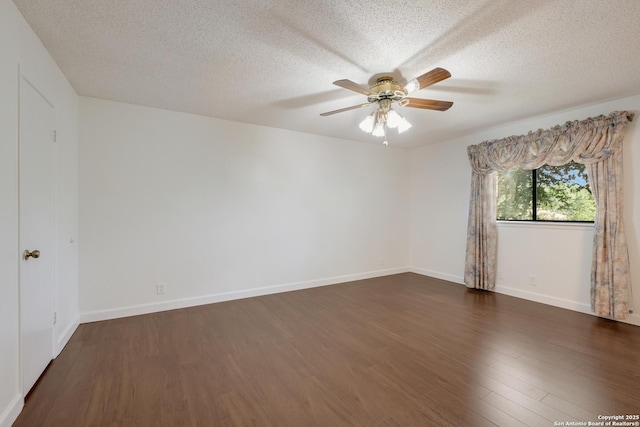 spare room with dark wood finished floors, a ceiling fan, a textured ceiling, and baseboards