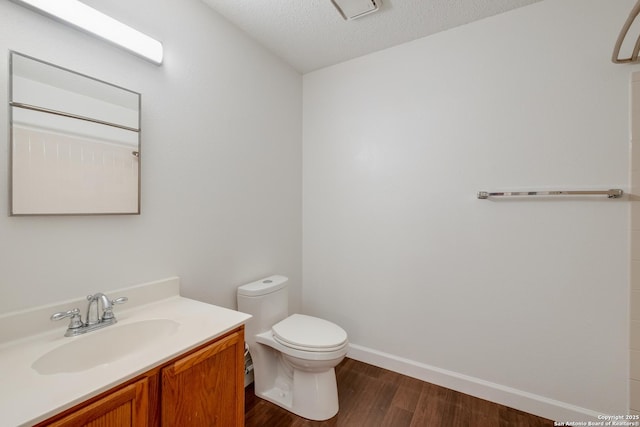bathroom featuring wood finished floors, toilet, vanity, a textured ceiling, and baseboards