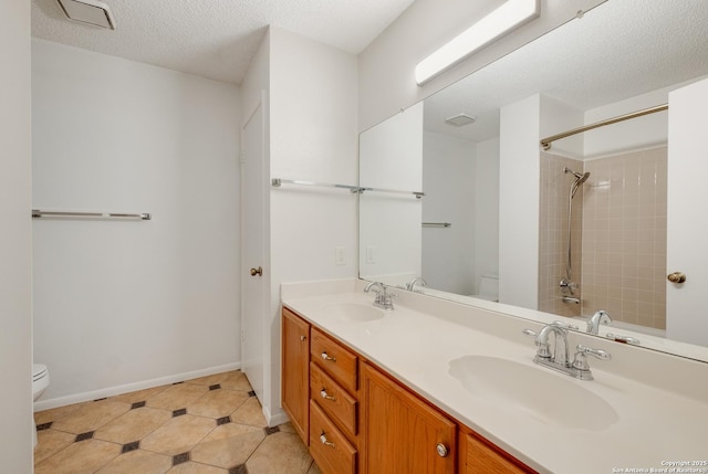 full bathroom with toilet, a shower, double vanity, a textured ceiling, and tile patterned flooring