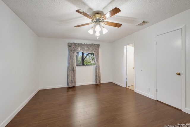 empty room featuring dark wood finished floors, a ceiling fan, a textured ceiling, and baseboards