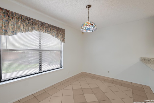 unfurnished dining area featuring a textured ceiling and light tile patterned flooring
