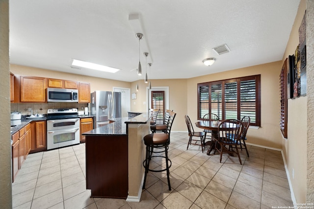 934 Saxonhill, San Antonio, TX 78253 - kitchen with stainless steel appliances, light tile patterned floors, a breakfast bar, backsplash, and baseboards