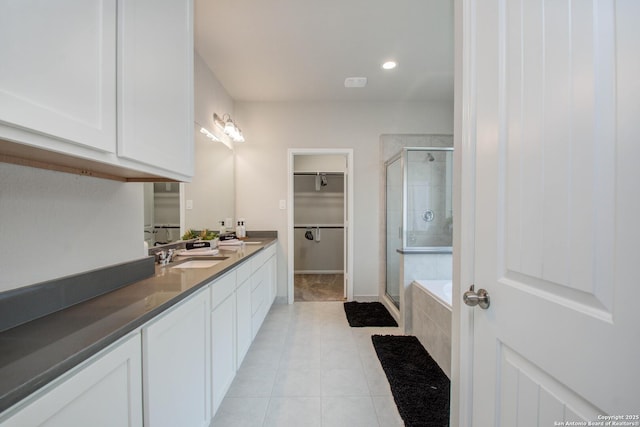 7606 Cottonwood Fls, Spring, TX 77379 - full bathroom with a shower stall, a walk in closet, tile patterned flooring, double vanity, and a relaxing tiled tub