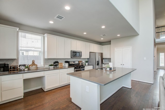 7606 Cottonwood Fls, Spring, TX 77379 - kitchen featuring stainless steel appliances, dark wood-type flooring, tasteful backsplash, a center island with sink, and white cabinetry