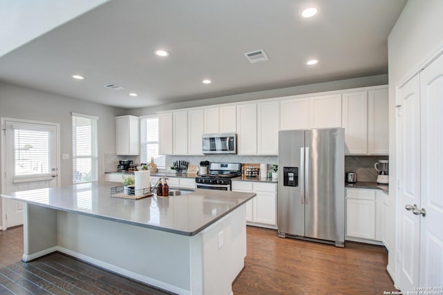 7606 Cottonwood Fls, Spring, TX 77379 - kitchen featuring appliances with stainless steel finishes, dark wood-style flooring, tasteful backsplash, white cabinetry, and recessed lighting