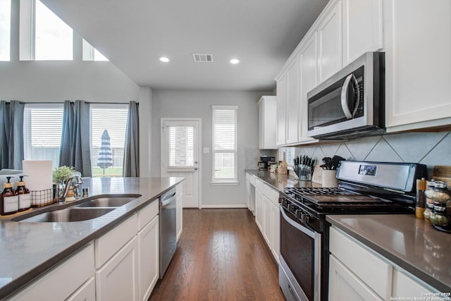 7606 Cottonwood Fls, Spring, TX 77379 - kitchen with stainless steel appliances, a sink, white cabinetry, dark wood-style floors, and decorative backsplash