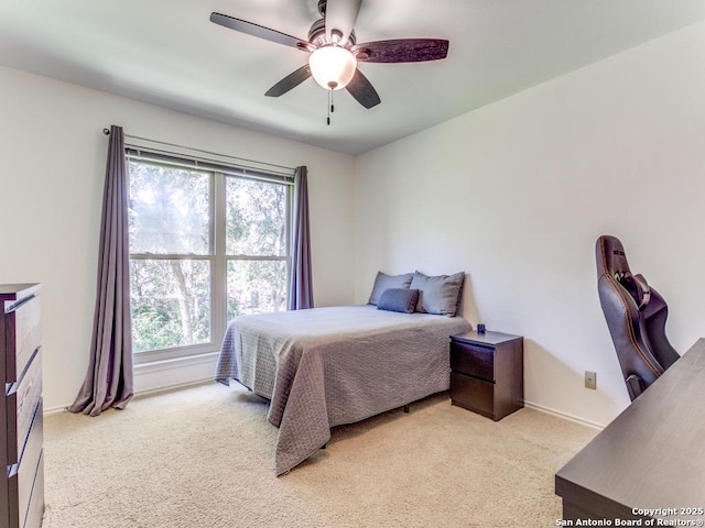 bedroom featuring multiple windows, light carpet, baseboards, and ceiling fan