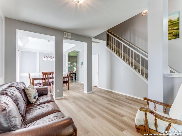 living area with light wood-style flooring, stairs, a chandelier, and baseboards