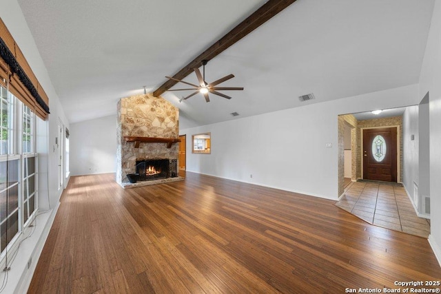 unfurnished living room with ceiling fan, wood-type flooring, plenty of natural light, and a stone fireplace