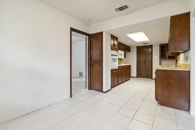 10514 Merritime Ct, San Antonio, TX 78217 - kitchen featuring white appliances, light countertops, a sink, dark brown cabinets, and glass insert cabinets