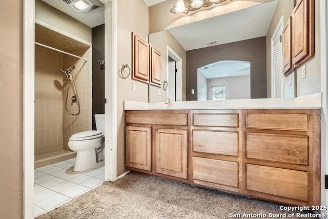 full bath with toilet, tiled shower, tile patterned flooring, and vanity