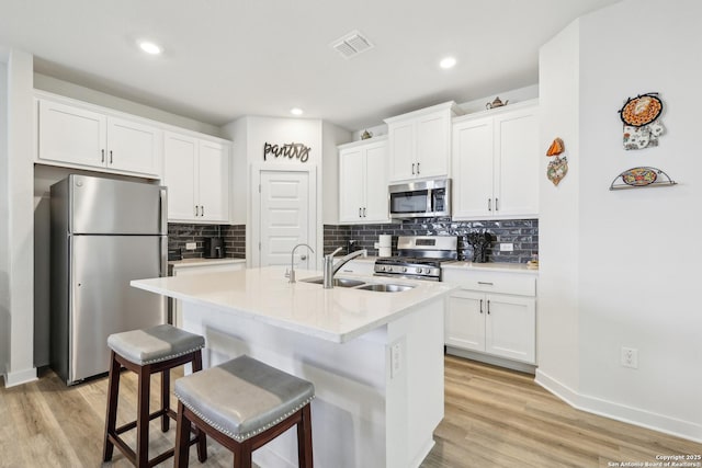 306 Banff, Kyle, TX 78640 - kitchen featuring appliances with stainless steel finishes, a sink, white cabinetry, a breakfast bar area, and light wood-type flooring