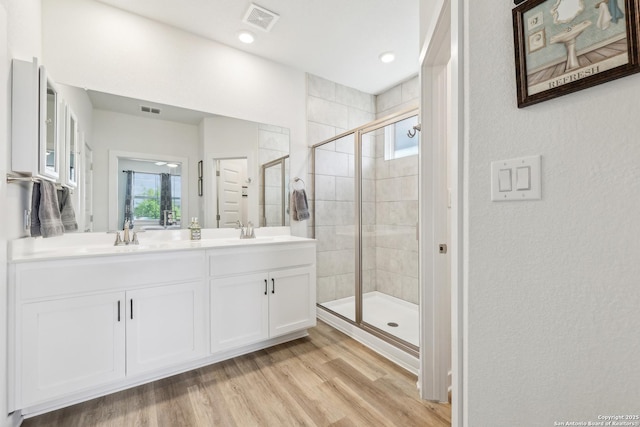 306 Banff, Kyle, TX 78640 - full bathroom with a shower stall, double vanity, wood finished floors, and a textured wall