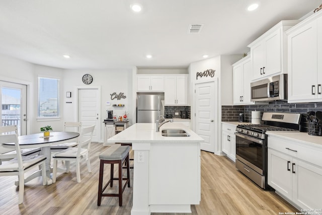 306 Banff, Kyle, TX 78640 - kitchen featuring stainless steel appliances, a sink, light wood-style floors, tasteful backsplash, and recessed lighting