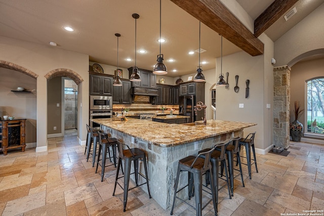 1040 Glenwood, Bulverde, TX 78163 - kitchen with stone tile floors, arched walkways, stainless steel appliances, tasteful backsplash, and a large island with sink